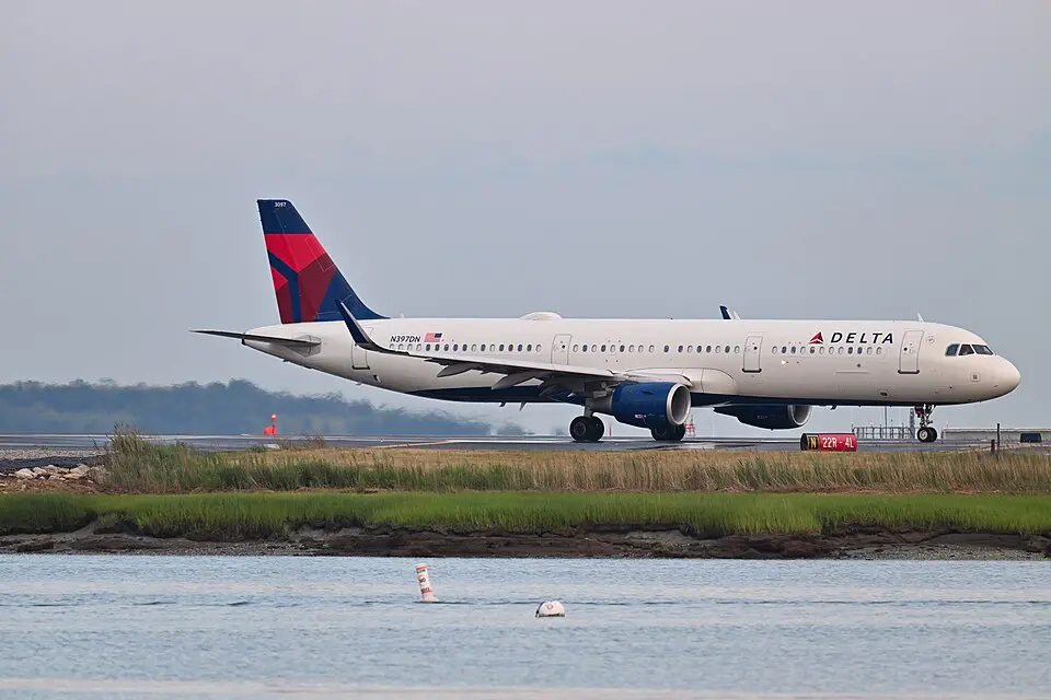 Delta Air Lines Airbus A321 touching down at LaGuardia Airport, with marshland and water in the foreground
