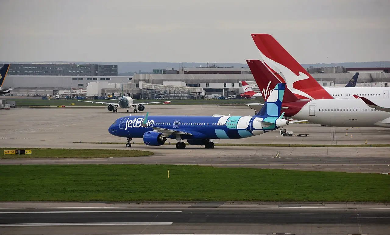 JetBlue Airways Airbus A321 taxiing at London Heathrow Airport, with Qantas and Virgin Atlantic tails visible behind it